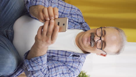 Vertical-video-of-Happy-old-man-texting-on-the-phone.-Smiling.